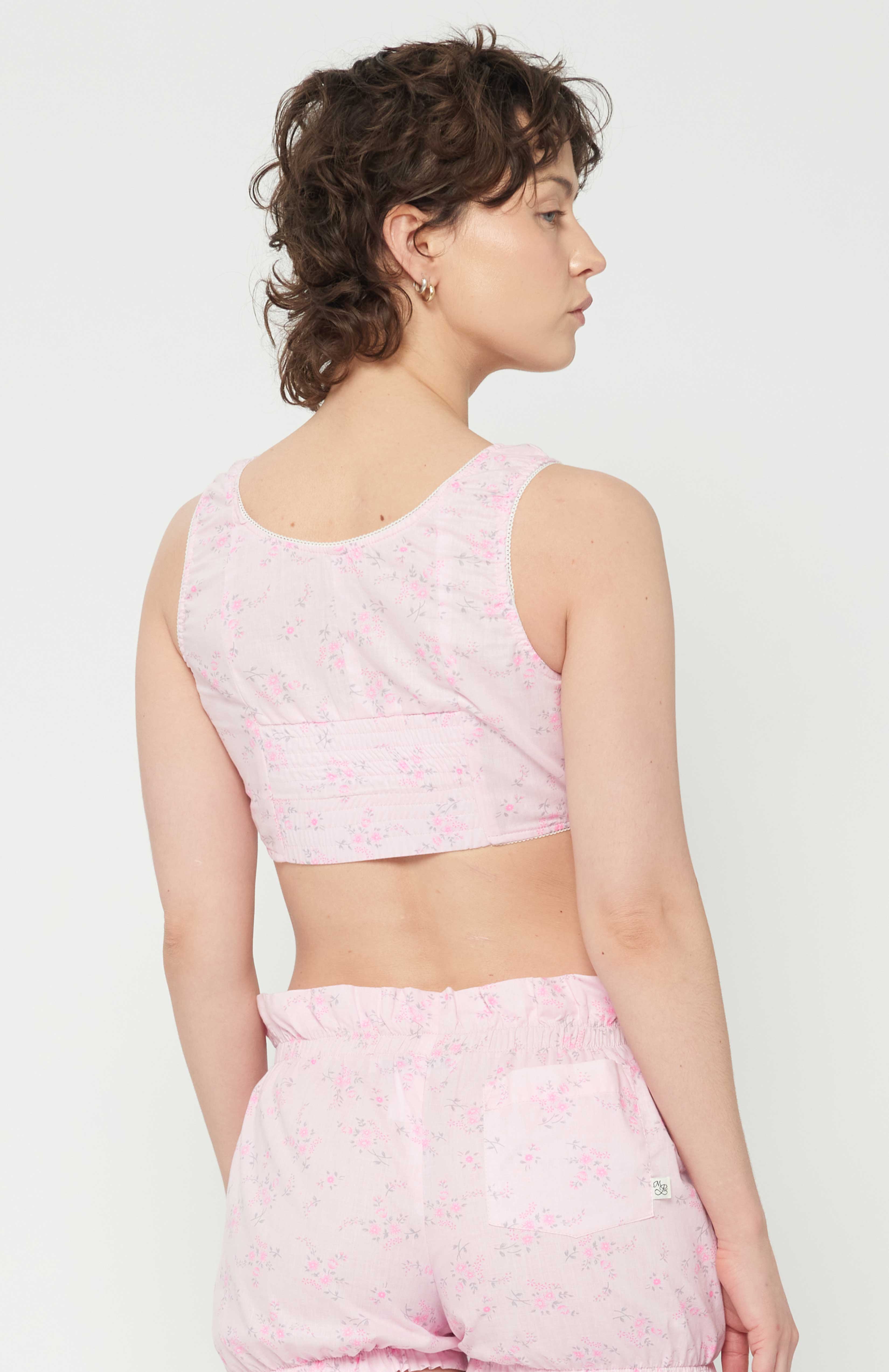 maroske peech This playful form-fitting cotton cropped floral bustier is an updated classic vintage style of an era gone by. The bust-line gathers facilities and creates a feminine shape. features scalloped elastic finishings as well as, a tidy hook and eye centre front closure. This piece was lovingly inspired by historic lingerie and was created with versatility in mind.