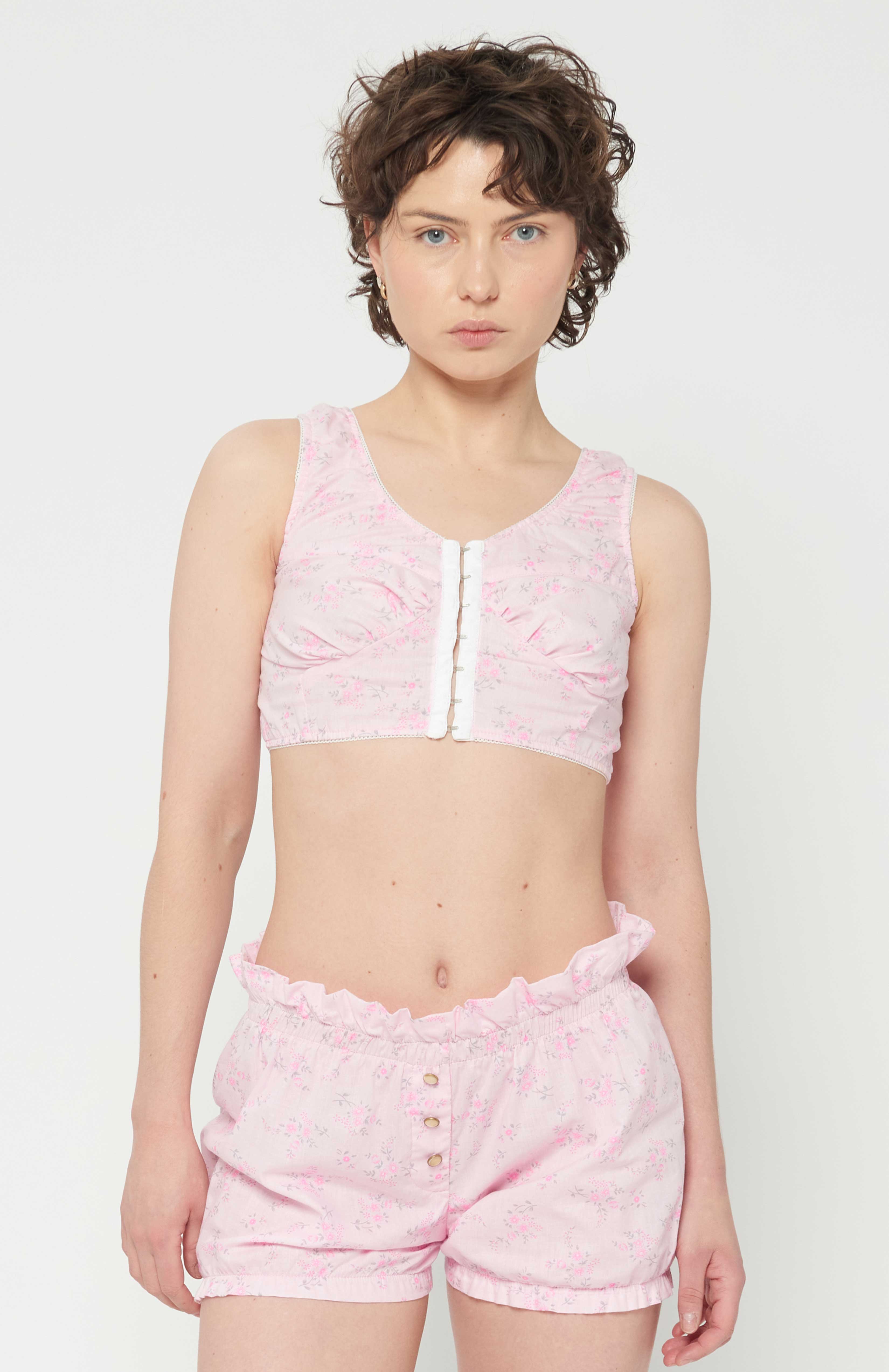 maroske peech This playful form-fitting cotton cropped floral bustier is an updated classic vintage style of an era gone by. The bust-line gathers facilities and creates a feminine shape. features scalloped elastic finishings as well as, a tidy hook and eye centre front closure. This piece was lovingly inspired by historic lingerie and was created with versatility in mind.