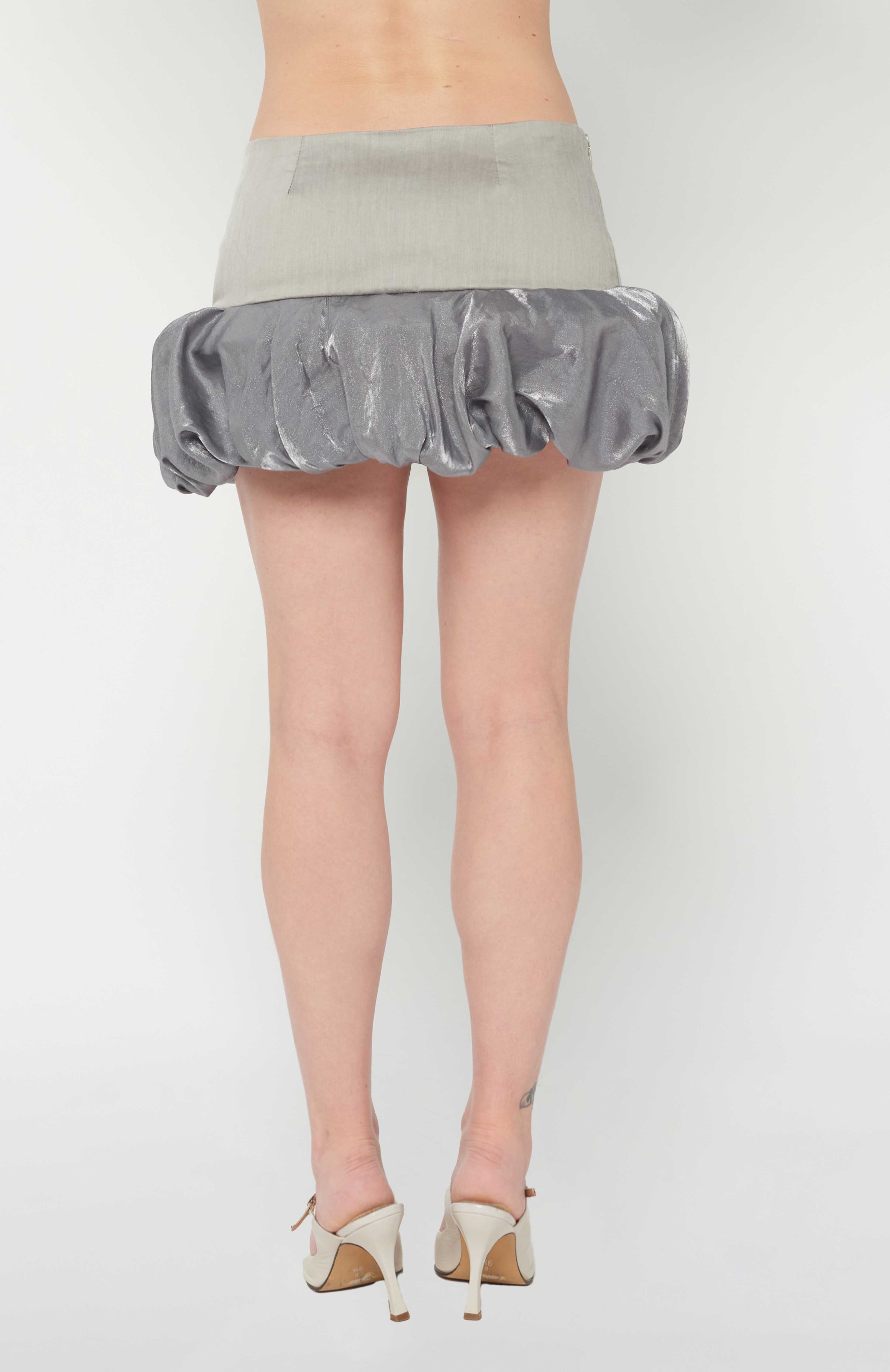 Maroske Peech A flirty playful bubble mid waisted mini skirt that salutes the fashion trends of the 1980s. This mid rise puffball style is created with a crinoline inner foundation to hold its balloon-like shape. A wonderful way to add volume to a silhouette.