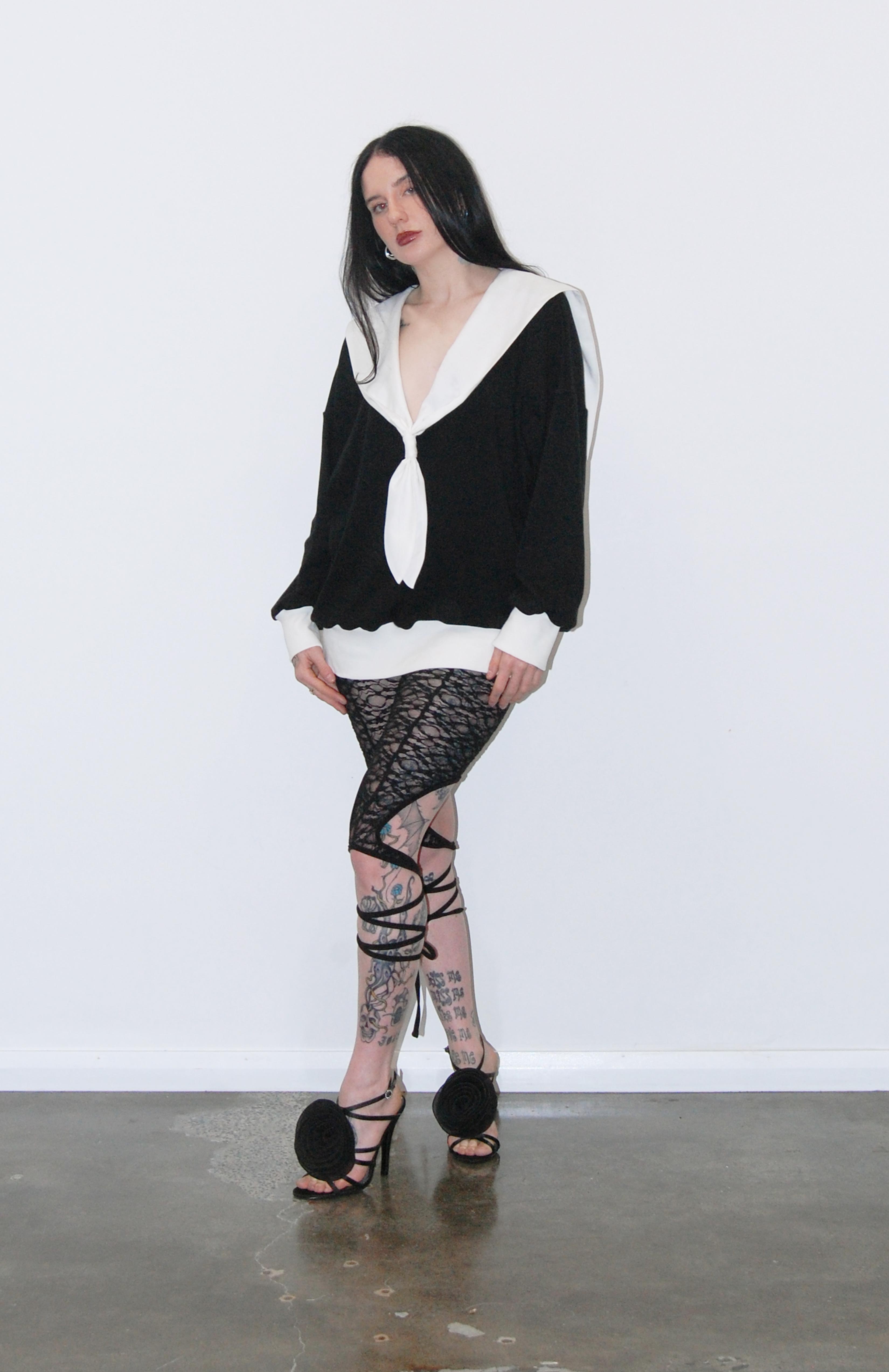 An oversized soft knit black jersey sweater with romantic white V-neck sailor collar. Features complimentary white rib accent cuffs and hem. This cosy style is a sophisticated alternative to a hoodie that can be easily dressed up or down. Perfect for provoking a glamorous yet bitter sweet adventure.