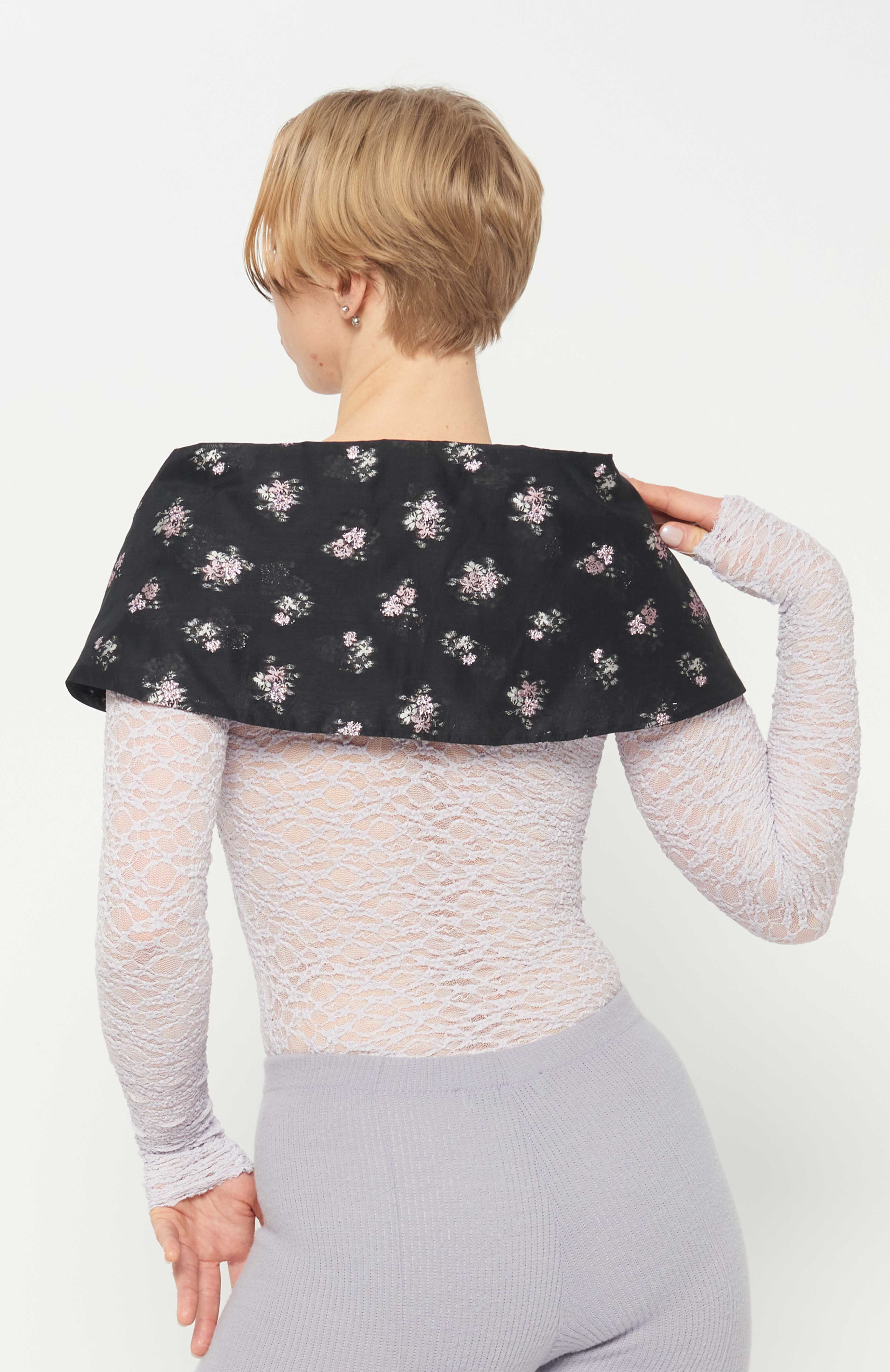 Maroske Peech, A stylish cape-like black floral bow collar. Sits on your shoulders to frame the neck and face. Fashioned in a light weight woven jacquard with a flattering detailed pink metallic floral. A perfect way to create a dramatic frame-like allure to elevate any outfit when your presence is required.
