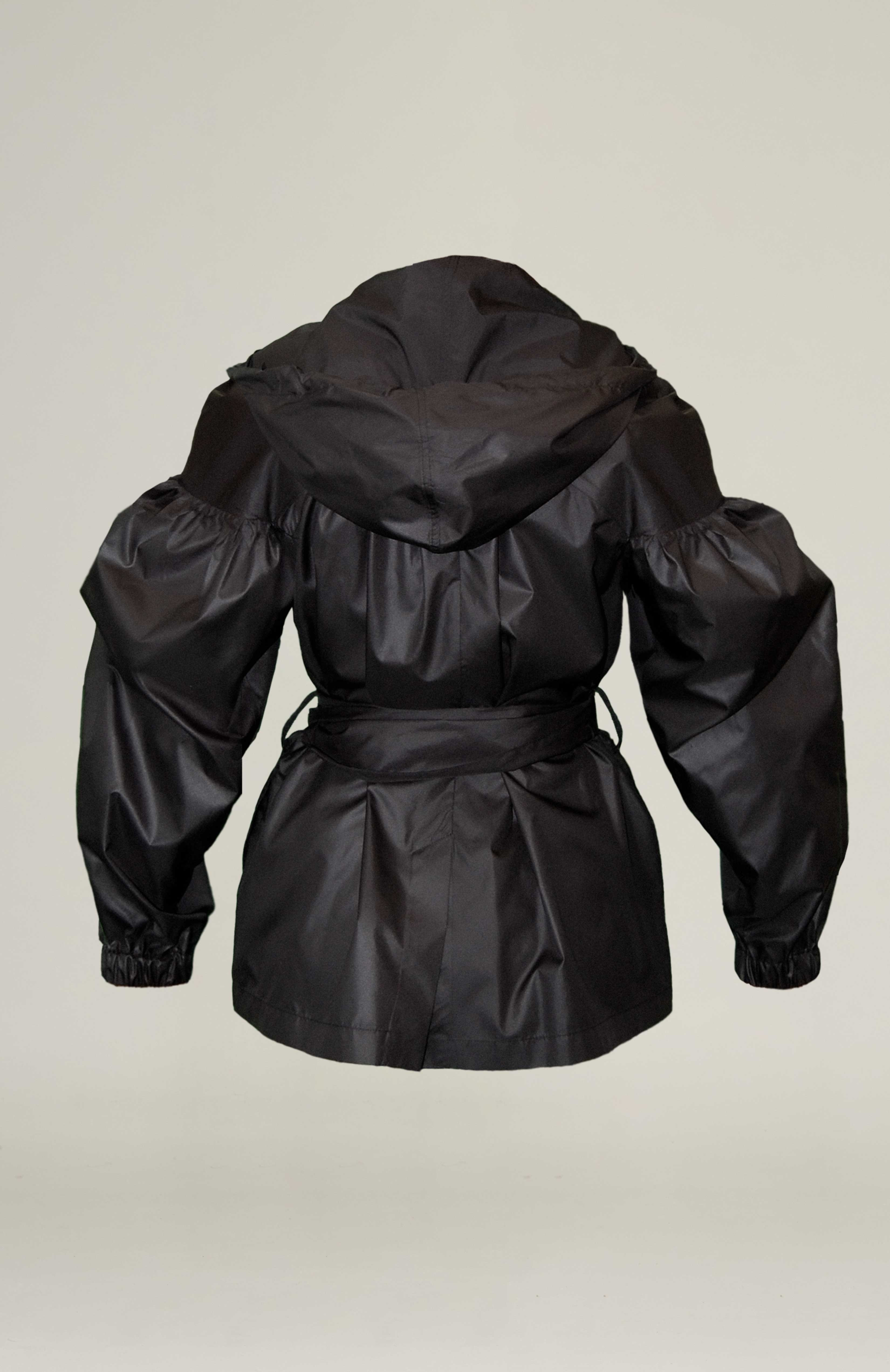 Back veiw, Light weight double breasted trench jacket with dramatic gathered sleeves. Adjustable pull string hood and elasticated cuffs. Side seam pockets and belt loops. Comes with waist belt fasten