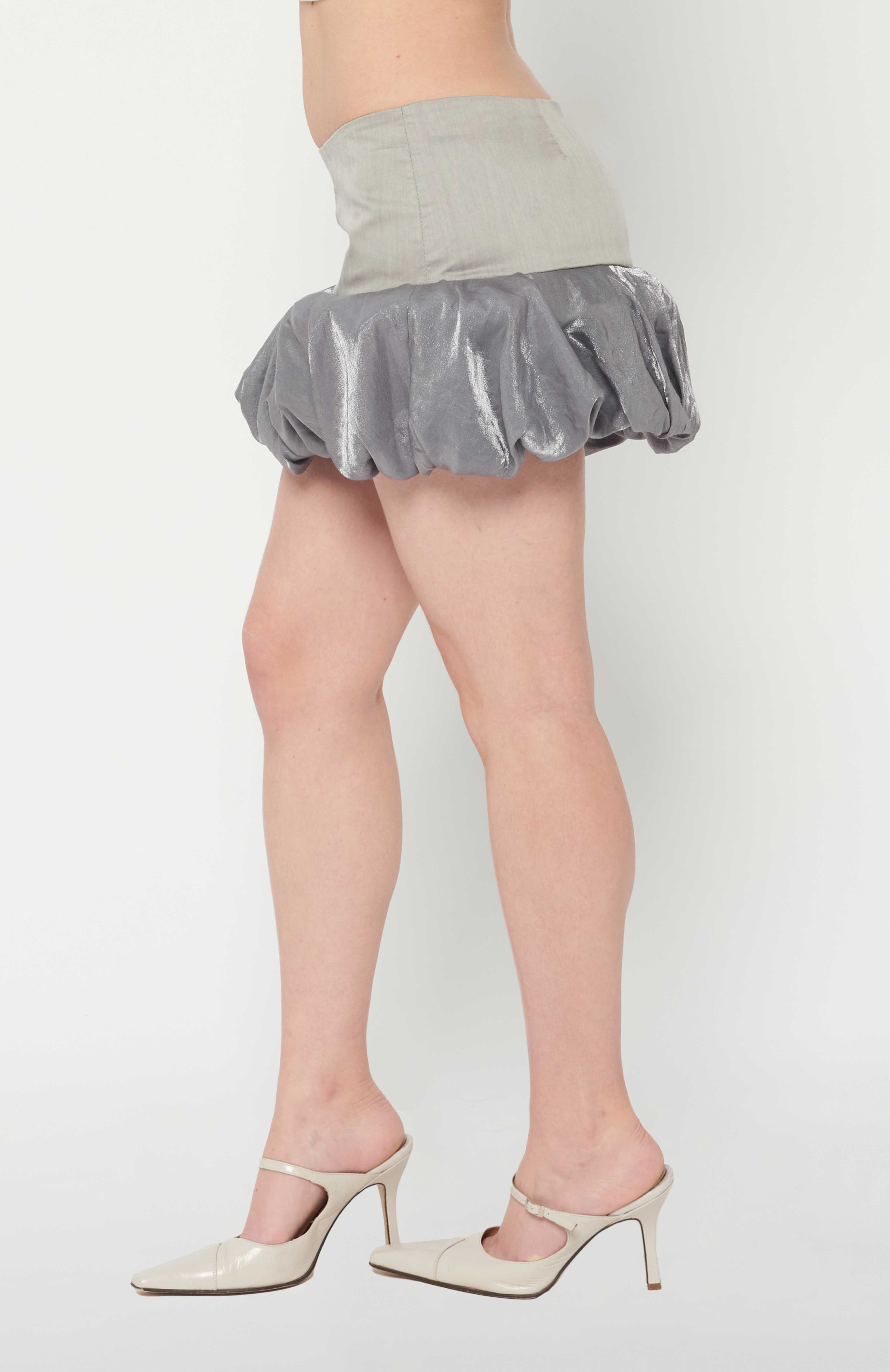 Maroske Peech A flirty playful bubble mid waisted mini skirt that salutes the fashion trends of the 1980s. This mid rise puffball style is created with a crinoline inner foundation to hold its balloon-like shape. A wonderful way to add volume to a silhouette.