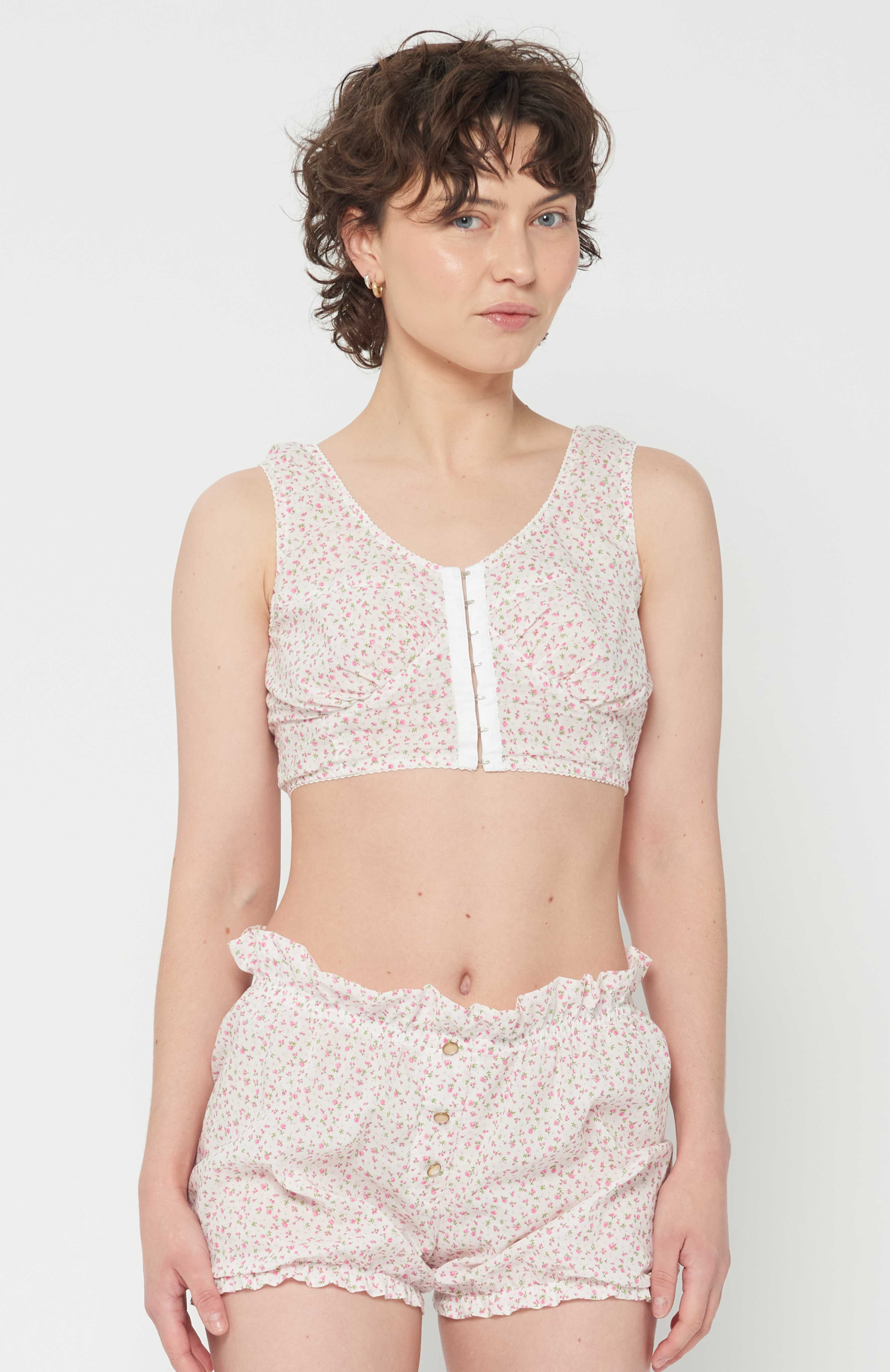 Maroske Peech playful cropped white floral bustier is an updated classic of an era gone by. The bust-line gathers facilitates and creates a feminine shape. Features scalloped lace elastic finishings, a tidy hook and eye centre front closure finishes off the sweatheart neckline. 