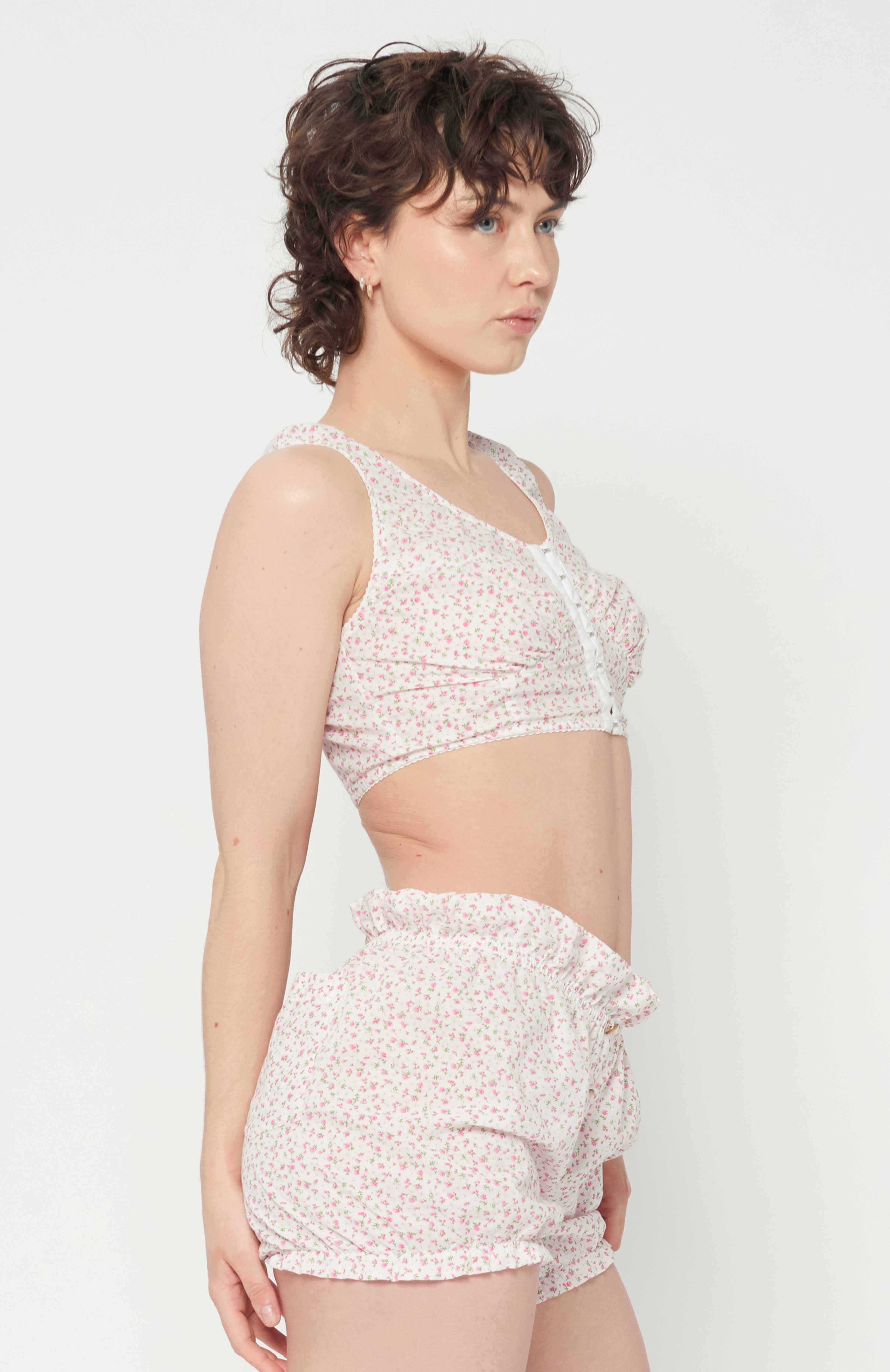 Maroske Peech playful cropped white floral bustier is an updated classic of an era gone by. The bust-line gathers facilitates and creates a feminine shape. Features scalloped lace elastic finishings, a tidy hook and eye centre front closure finishes off the sweatheart neckline.