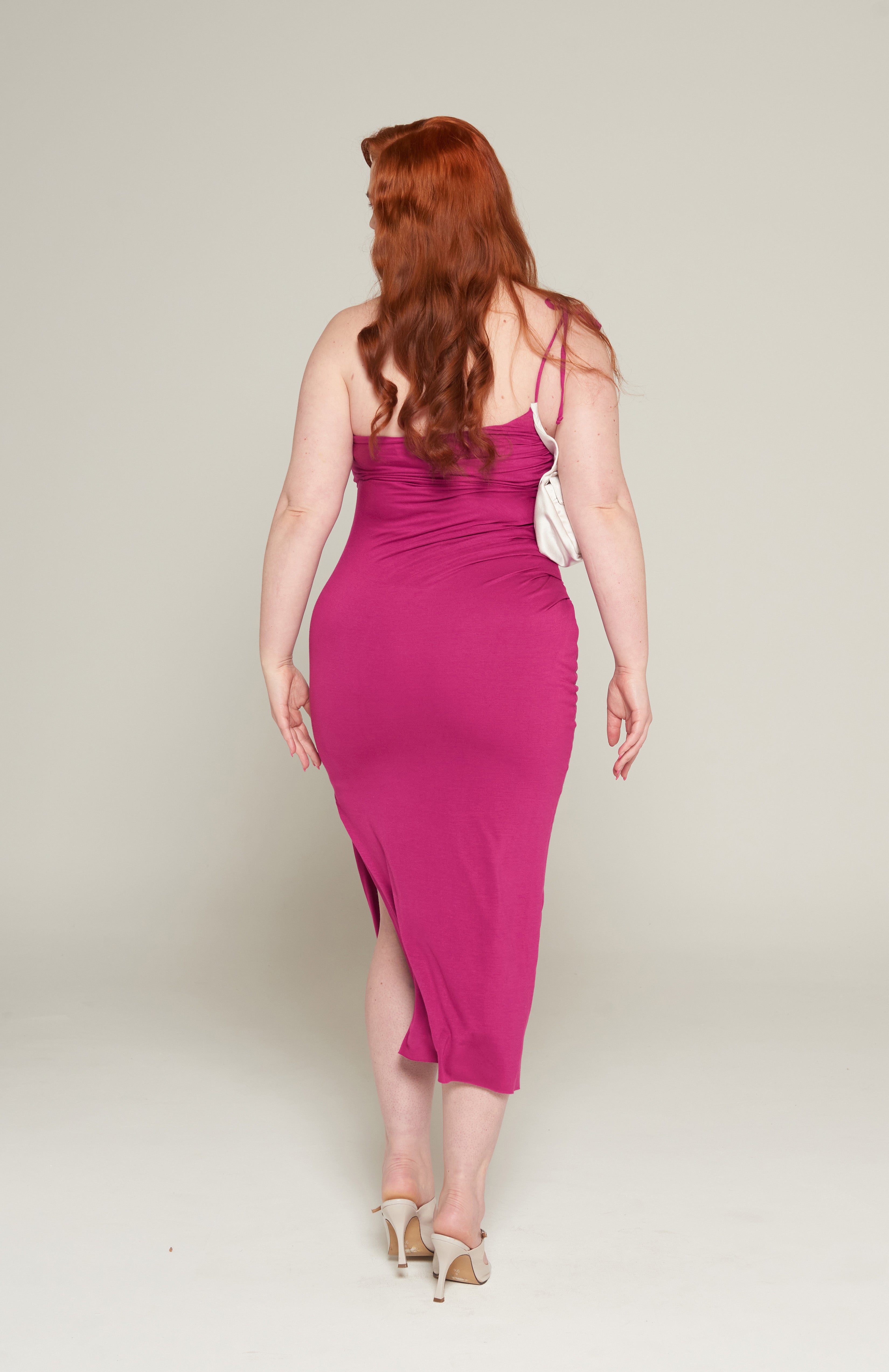 Mid length maxi dress in fuchsia jersey with attached Navy purse pocket. Features, flattering pleats from underarm to the high hip Thigh high slit and adjustable tie spaghetti strap. fully lined with square buckle and magnetic button. 